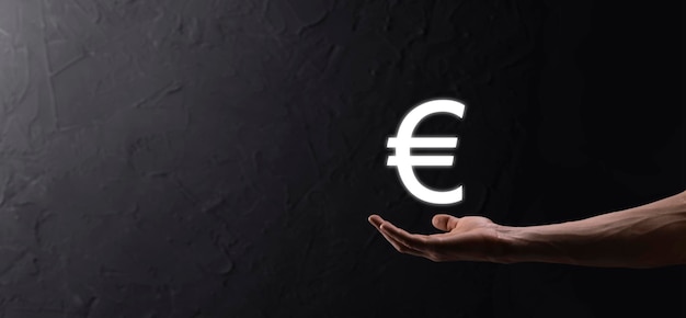 L'uomo d'affari tiene le icone delle monete in euro o in euro su sfondo scuro.. crescente concetto di denaro per investimenti aziendali e finanza