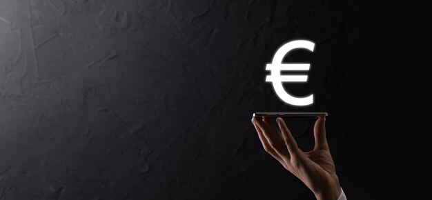 Businessman holds money coin icons EUR or Euro on dark tone background..Growing money concept for business investment and finance