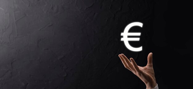 Бизнесмен держит значки монет евро или евро на фоне темных тонов. Концепция роста денег для инвестиций в бизнес и финансов