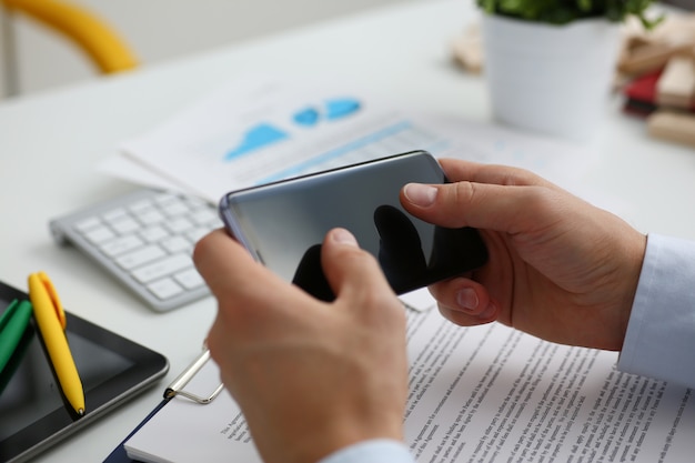 A businessman holds a new smartphone in his hand