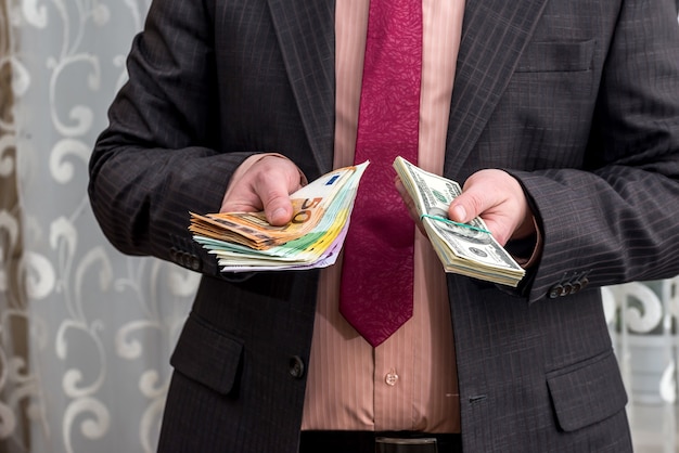 Businessman holds pack of dollars and euros in his hands