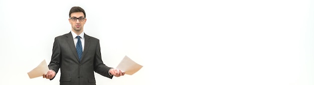 The businessman holds papers on the white wall background