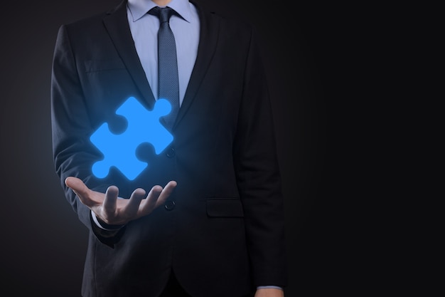 Businessman holds a piece of puzzle jigsaw in his hands.The concept of cooperation, teamwork, help and support in business.