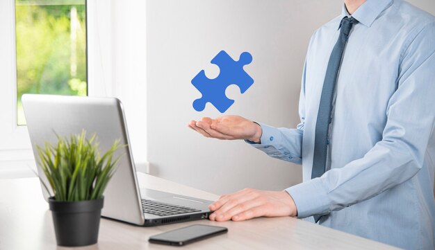 Businessman holds a piece of puzzle jigsaw in his hands.The concept of cooperation, teamwork, help and support in business.