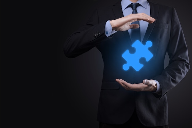 Businessman holds a piece of puzzle jigsaw in his hands.