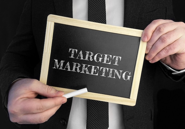 A businessman holds up a chalkboard with text target marketing