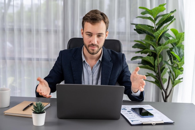 Businessman holds virtual online office meeting from office desk Entity