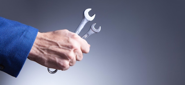 Businessman holds wrenches in his hands