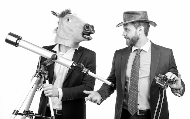 Businessman in horse head mask hold telescope and cowboy man with binoculars business vision