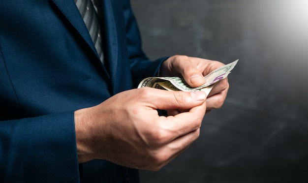 businessman is counting money on dark surface