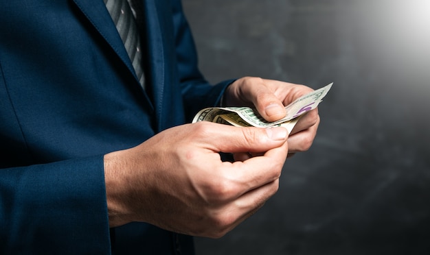 Businessman is counting money on dark surface