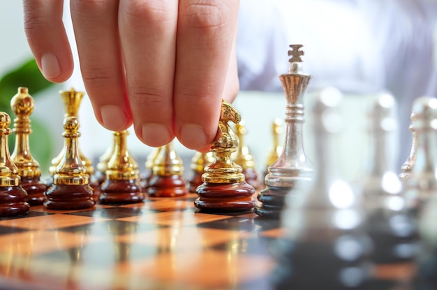 A businessman is holding a chess gold piece of a knight about to make a move Game of chess concept of confrontation strategic planning tactic