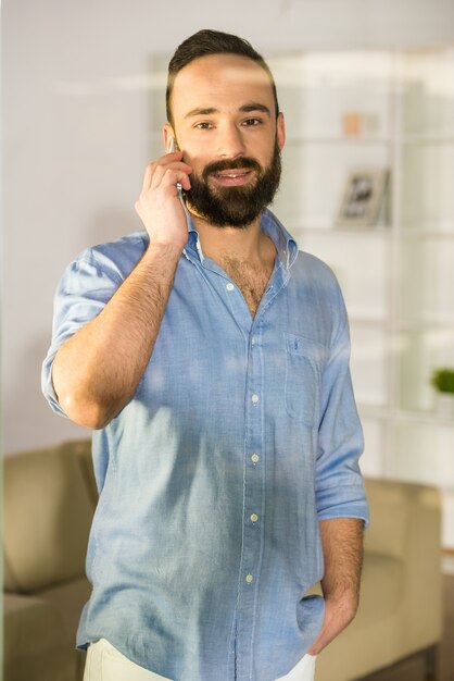 Businessman is talking by phone, seen through glass.