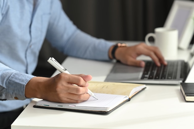 L'uomo d'affari sta lavorando con un nuovo progetto di avvio e sta pianificando un notebook.