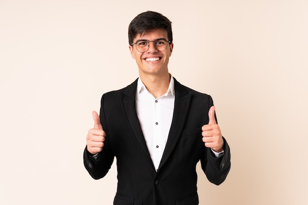 Businessman over isolated beige background giving a thumbs up gesture