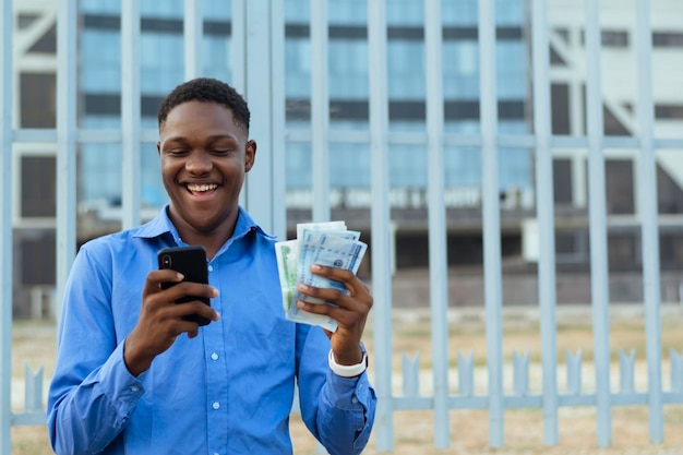 Businessman isolated over building standing sending money via phone with cash at hand