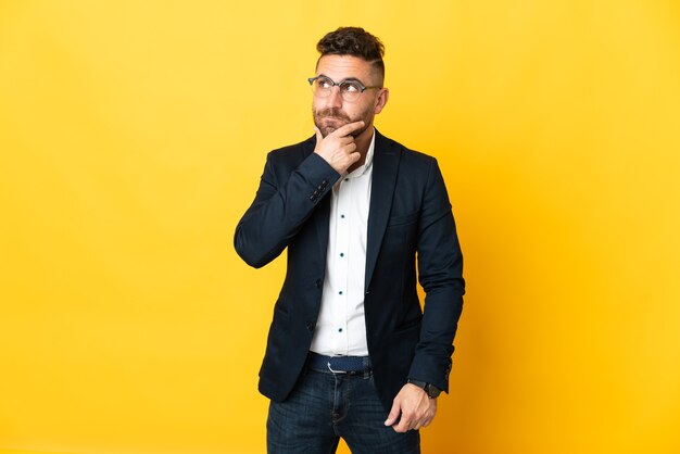 Businessman over isolated yellow background having doubts and thinking