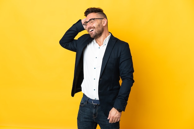 Businessman over isolated yellow background smiling a lot