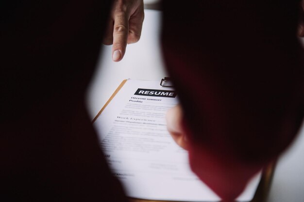 Businessman or job seeker review his resume on his desk before send to finding a new job with pen necktie glasses and digital tablet