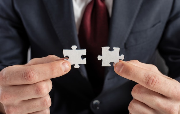 Businessman join two puzzle pieces. concept of teamwork and partnership.