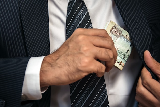 Businessman keeping the United Arab Emirates banknote money in his suit pocket 