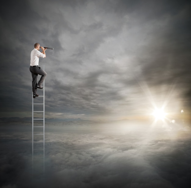 Businessman on a ladder high into the sky watching with binoculars