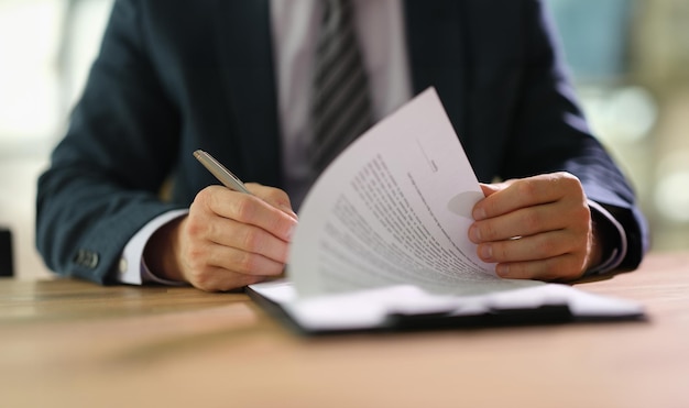 Businessman leafing through documents and signing contract for business deal at work in office