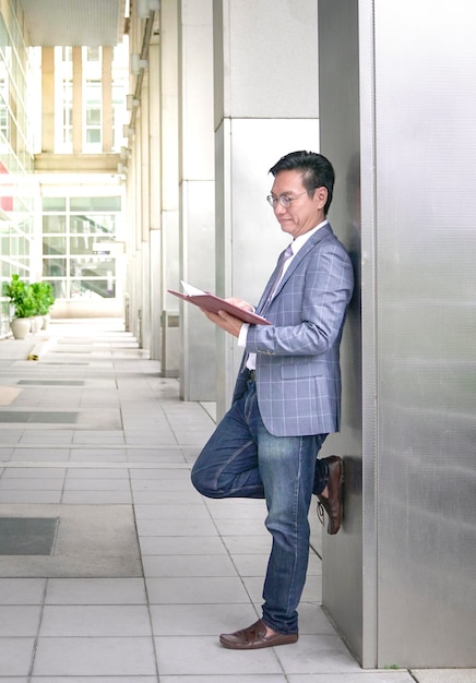 Businessman leaning against building pillar looking at his diary