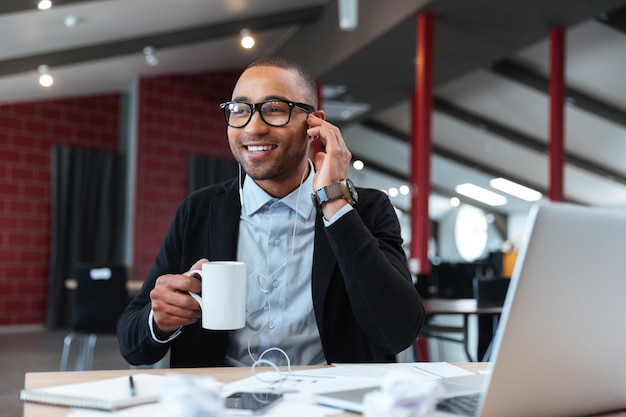 Businessman listening to music and holding cup in the office