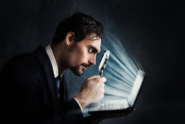 Photo businessman look with magnifying glass at the computer screen