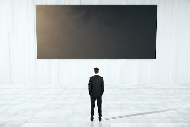 Businessman looking at black billboard