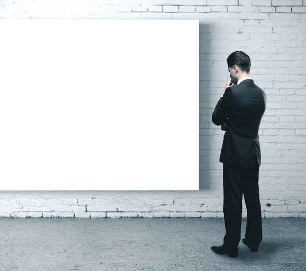 Photo businessman looking on blank poster on brick wall