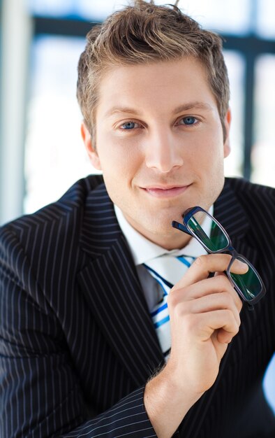 Businessman looking to the camera holding glasses