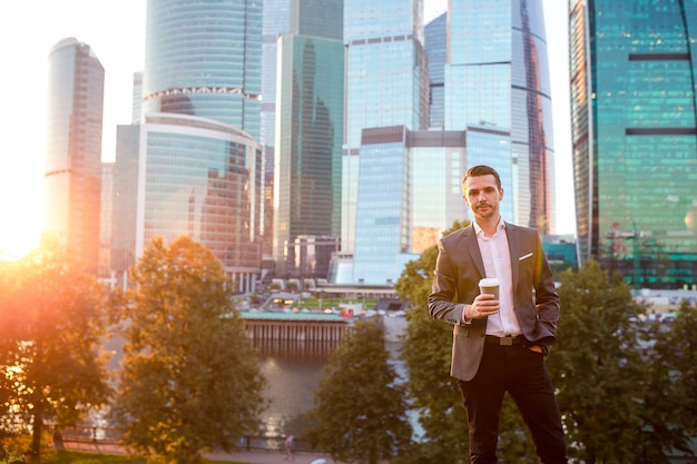 Businessman looking on copy space while standing against glass skyscraper