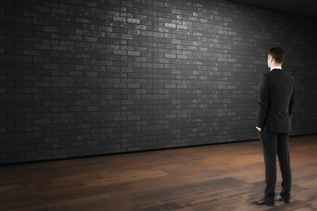 Businessman looking at empty brick wall