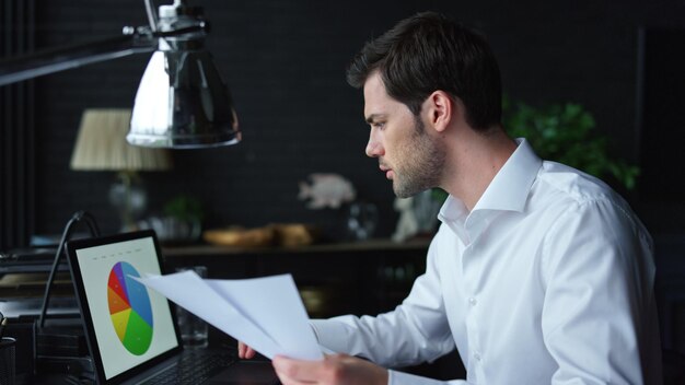 Foto uomo d'affari guardando la grafica sullo schermo del laptop manager che lavora con le carte