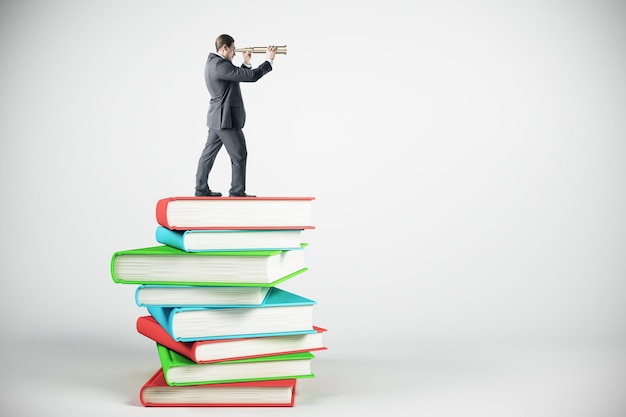 Businessman looking into the distance while standing on book stack Education research and career concept