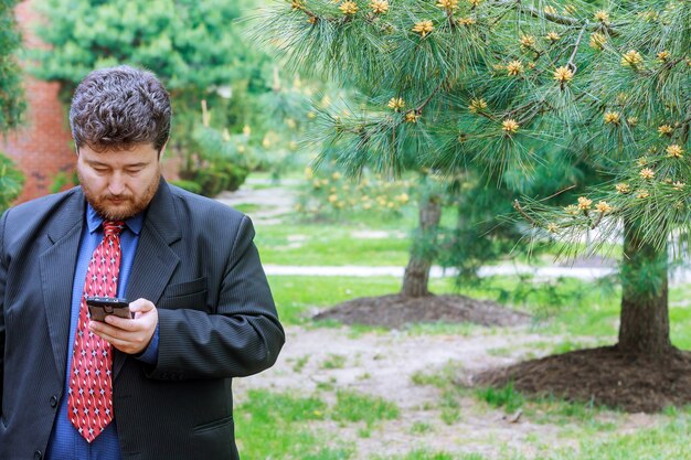 Businessman looking into the phone, man working on the street.