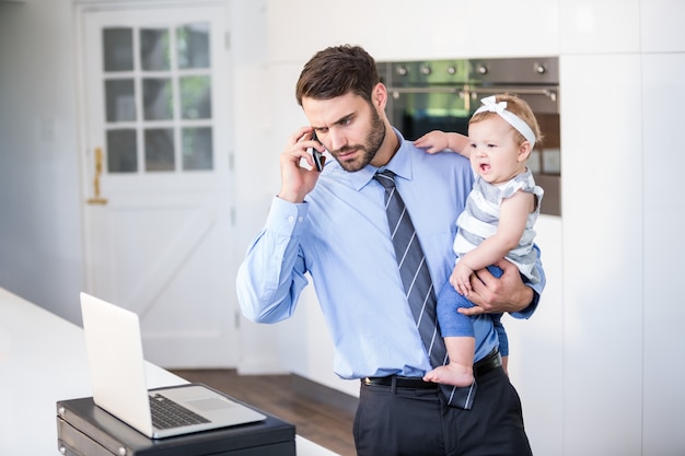 Photo businessman looking in laptop while carrying daughter