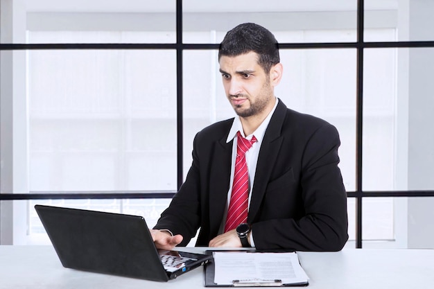 Бизнесмен смотрит на ноутбук с растерянным выражением лица