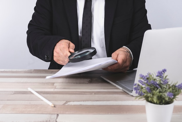 Businessman looking through a magnifying glass for documents