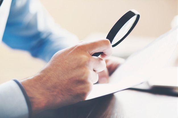 Businessman looking through a magnifying glass