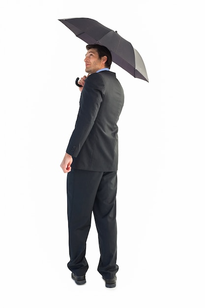 Бизнесмен, глядя вверх, держа черный зонтик