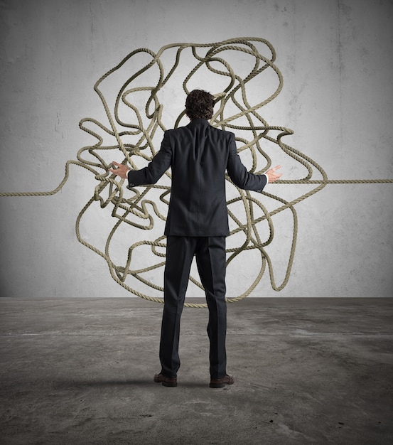 Businessman looks confused tangle of rope. Find a solution concept