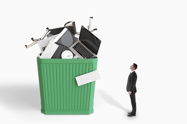 Photo businessman looks at huge green wastebusket with office accessories