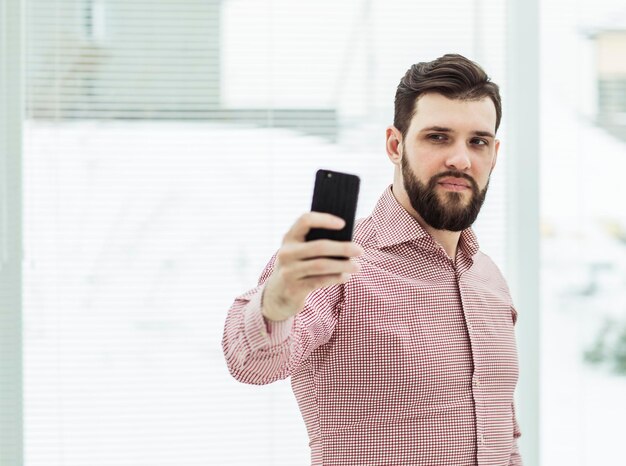 Businessman makes selfie while standing near window in office