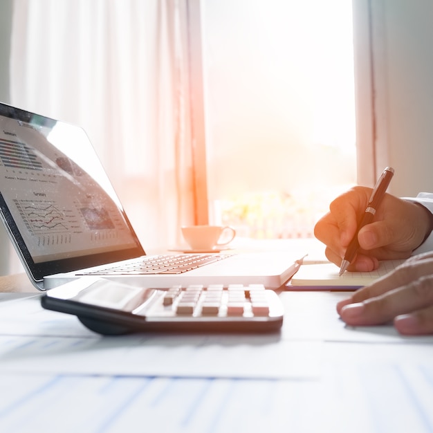 Businessman making notes on the paper at window edge in his office