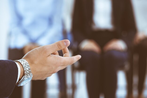 Businessman making presentation to group of people in office. Speaker delivering a seminar to his colleagues or business training. Teamwork and coaching concepts in business.