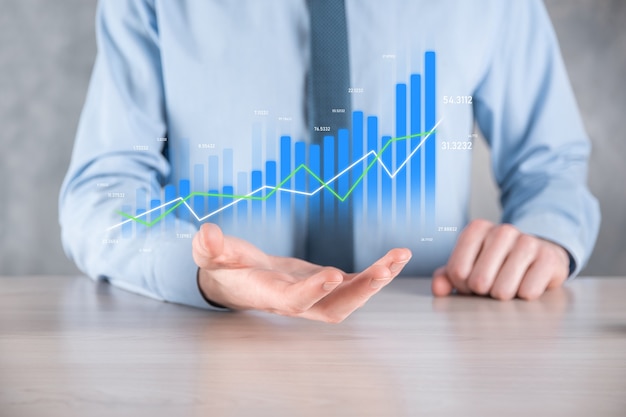 Businessman man holding a graph with positive profits growth. plan graph growth and increase of chart positive indicators in his business.more profitable and growing