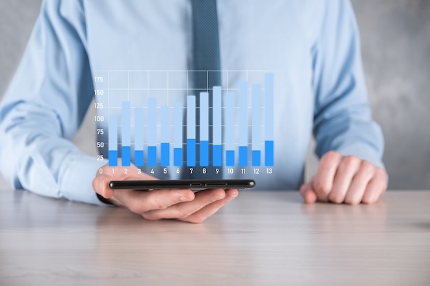 Businessman man holding a graph with positive profits growth